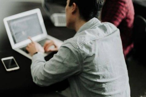 man sitting at laptop with a colleague