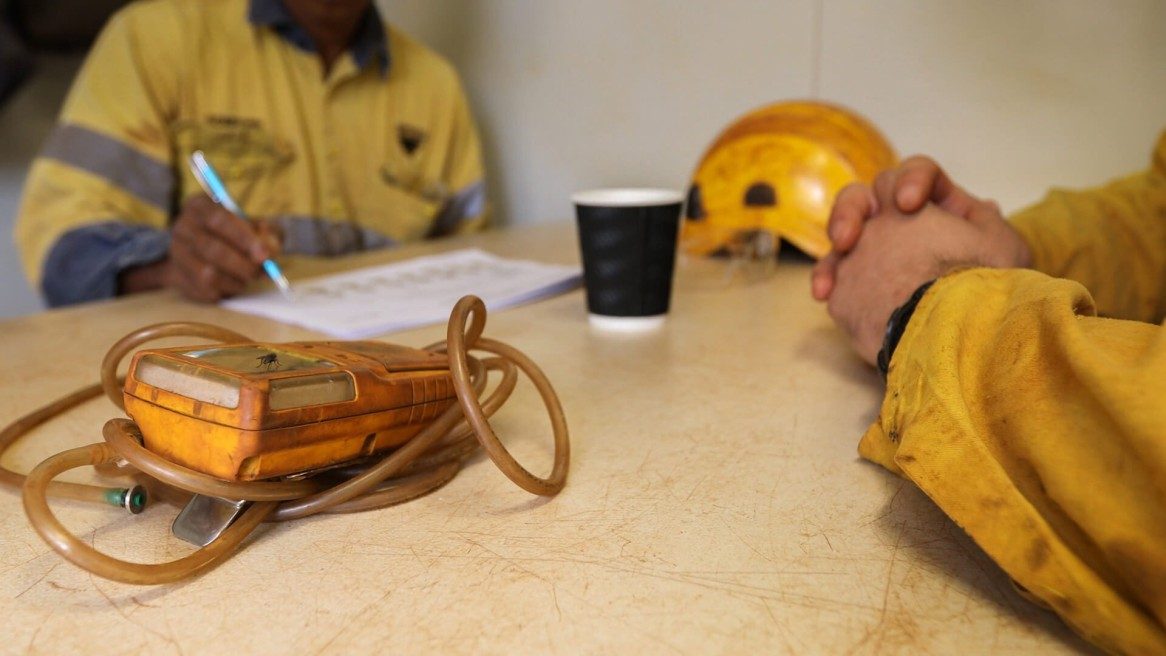 two workers stitting at a desk with equipment 